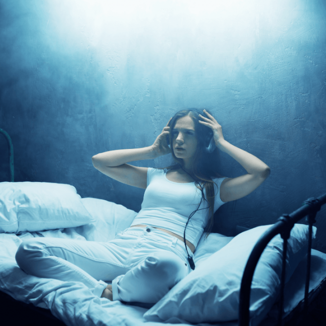 Girl with a headset listening to audio porn on here bed at night